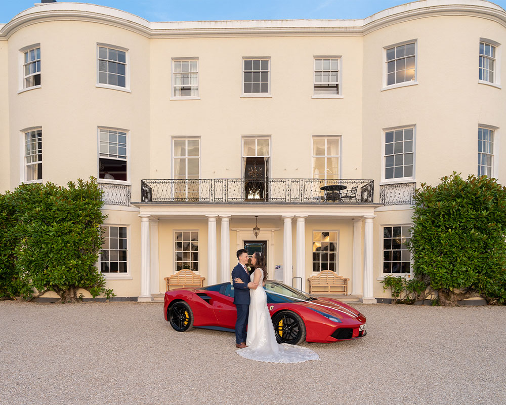 Bride and Groom next to a red Farrari at Rockbeare Manor, Exeter.